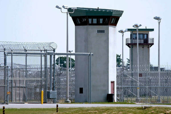 Two concrete guard towers and layers of chain link fencing topped with razor wire at a prison.