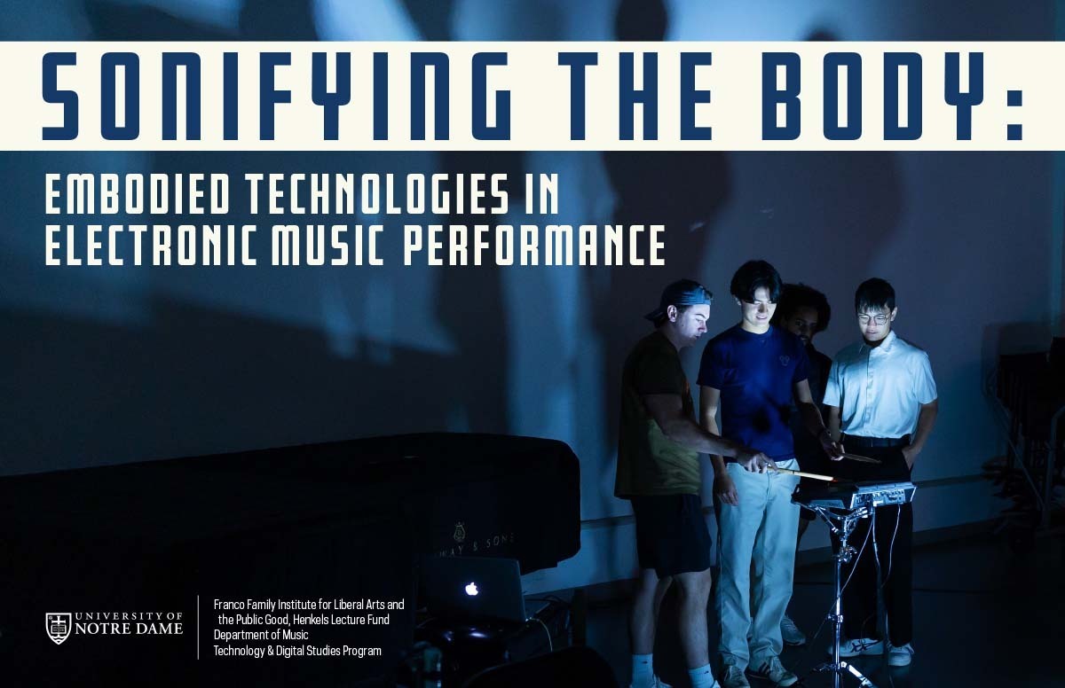 Four young men in a dark room gather around glowing electronic music equipment. One in a white shirt and glasses holds drumsticks over a pad, while three others watch. Blue light illuminates their faces.
